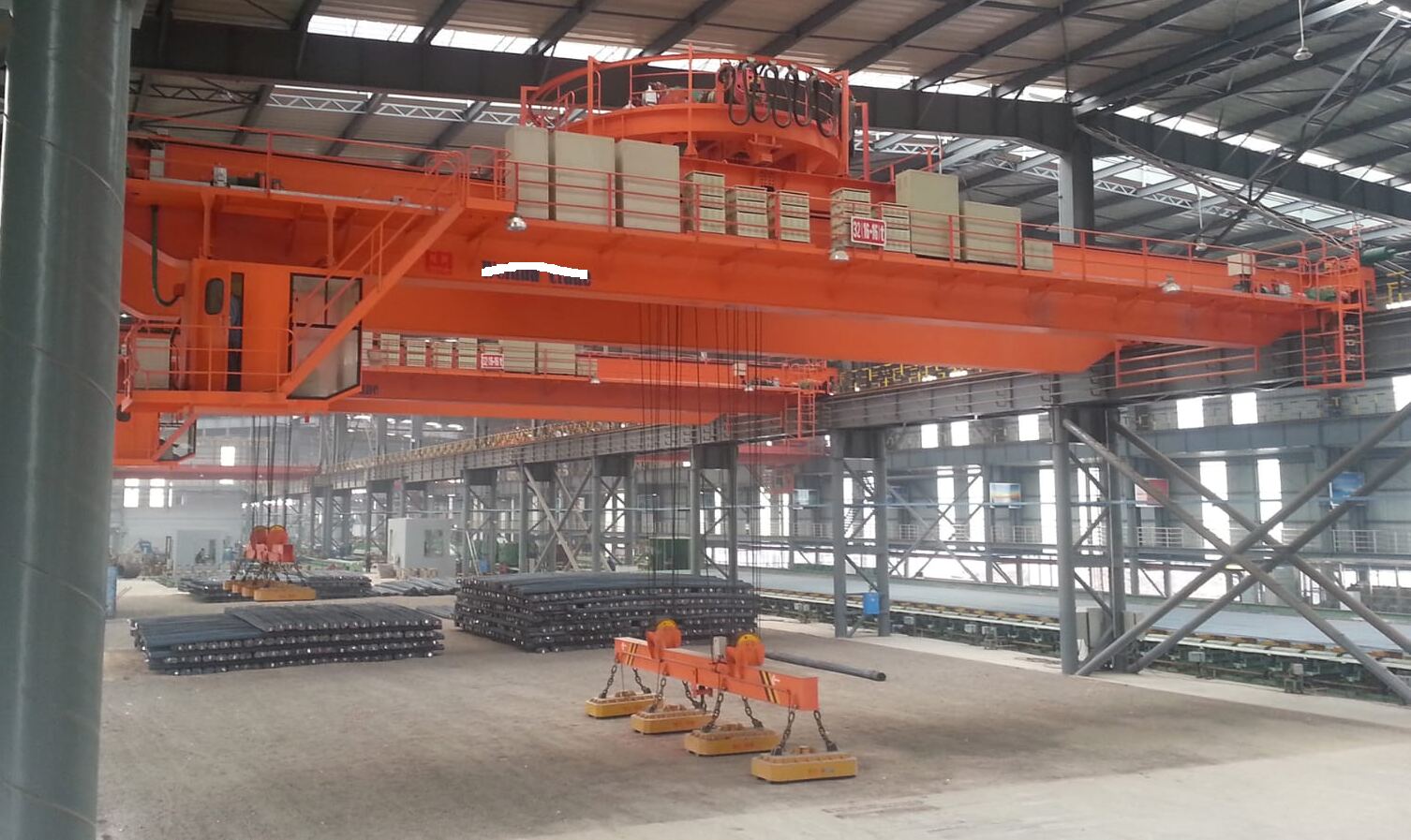 Double girder crane with magnetic spreader beam over a rebar yard