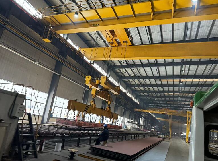 Rotating crane with spreader beam handling steel plate