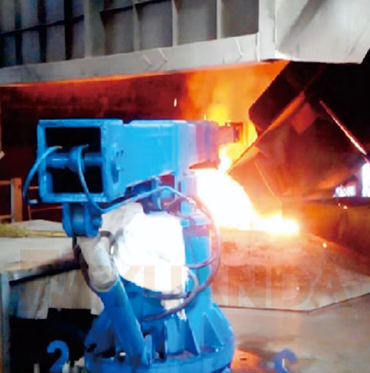 Robotic arm beside an induction furnace during charging